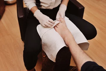 Fotobehang een jong meisje maakt een man-pedicure op de achtergrond van een schoonheidssalon. Nagelverzorging © Evgeniy Kalinovskiy