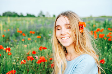 Naklejka na ściany i meble Calm happy blond woman in the field of poppy flowers