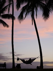 Person on hammock enjoying the sunset at the beach park in Hawaii 