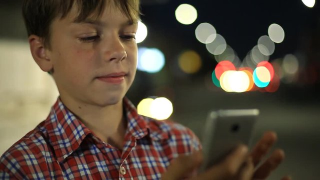 boy with a smartphone in hand on the background of night city lights.