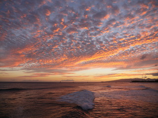 colorful sunset fluffy sky above the wavy ocean in hawaii