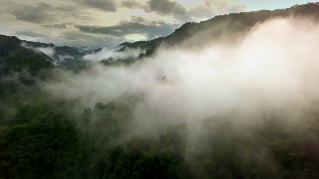 Aerial view of a village in the lush green rain cloud cover tropical rain forest mountain during the rainy season in the northern Thailand