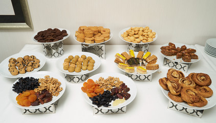 Mix of dry nuts and fruits dessert . Composition with dried fruits and assorted nuts and sweets cookies on white plates, top view