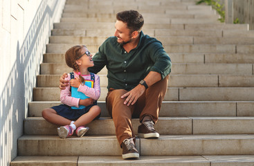 first day at school. father leads  little child school girl in first grade