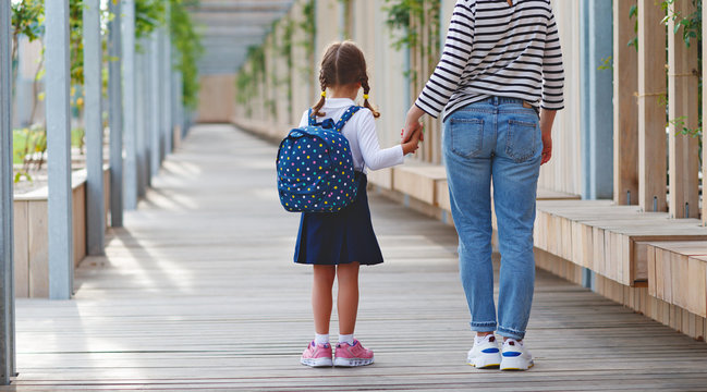 first day at school. mother leads  little child school girl in first grade.