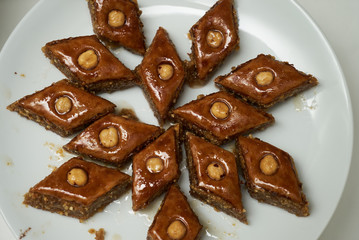 Traditional Azerbaijan dessert baklava with walnuts and cardamom on white plate. Homemade baklava with nuts and honey.