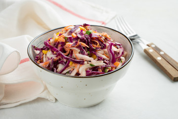 Purple cabbage and carrot salad with mayonnaise in a white bowl on a light background. Classic coleslaw. Diet vegetarian dish