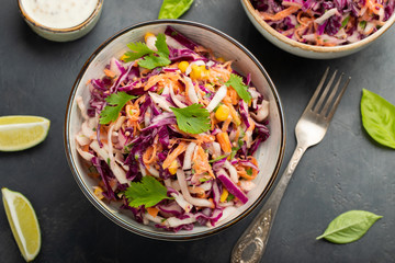Purple cabbage and carrot salad with mayonnaise in a white bowl on a black background. Classic coleslaw. Diet vegetarian dish. Top view