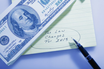  US Dollar bills, pen and notebook with description: New tax laws attached concept.
