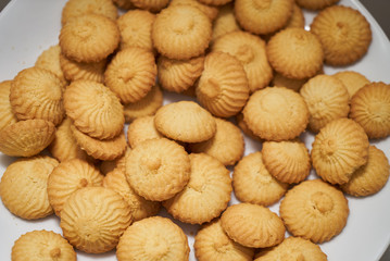 Fototapeta na wymiar Cookies and sweet biscuits on white plate background, top view 