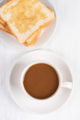 Cup of coffee and sliced bread with honey topping on white table