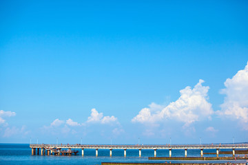 people walk on a long sea pier on a sunny day