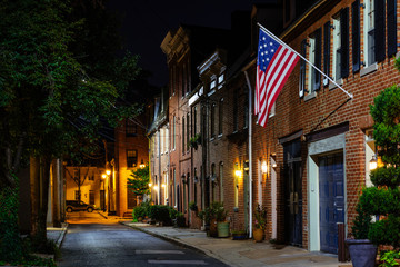 Fototapeta na wymiar American flag and row houses on Bethel Street at night, in Fells Point, Baltimore, Maryland