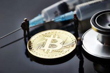 Fototapeta premium Bitcoin with miniature men and medical equipment 