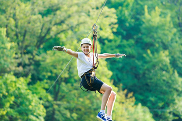 Happy, cute, young boy in white t shirt and helmet having fun and playing at adventure park, holding ropes and climbing wooden stairs. active lifestyle concept