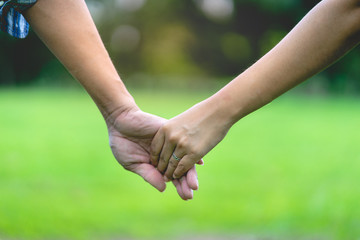 close up hand of female and male holding  together in park