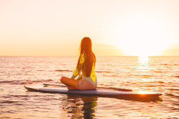 Stand up paddle boarding on a quiet sea with sunset colors. Relaxing on ocean