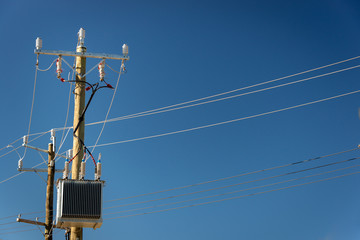 Power poles with power transformer against a blue sky