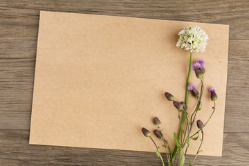 Wildflowers with handmade craft notebook on old grunge wooden background. Top view. Minimalistic mockup.