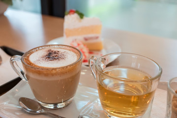 coffee cup and piece of strawberry cheesecake on white plate in cafe.