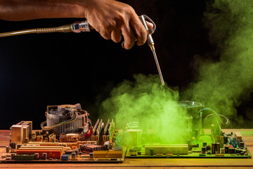 computer mainboard on wooden table on black background.. using air compressor cleaning the computer...