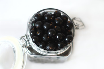berries black currant in a glass jar with a lid, isolate on a white background