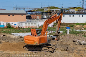 Excavator at the construction site carries a wheelbarrow in a ladle