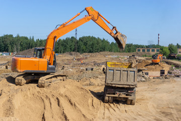 Obraz premium Excavator at the construction site will load the truck with sand