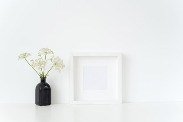 Minimal white square frame mock up with a episcopal weed in black vase near whitw wall. Mockup for quote, promotion, headline, design. Template for small businesses, lifestyle bloggers, social media