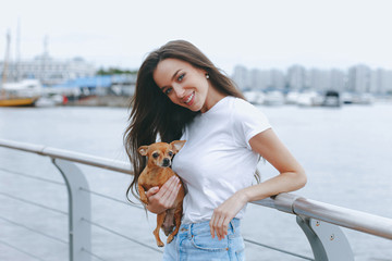 Fototapeta na wymiar Young attractive woman is walking with dog on sea promenade