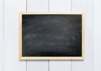 Fototapeta na wymiar Blackboard / chalkboard texture. Empty blank black chalkboard with chalk traces on white wood table