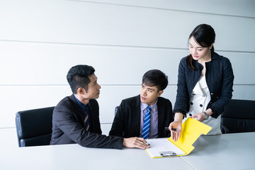 Confident businessman sitting at table and signing paperwork of his partner and smiling after making profitable agreement.