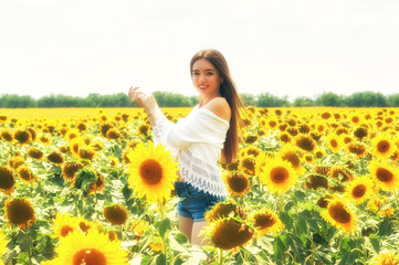 Fototapeta premium Beautiful young girl outdoors . A young girl is having fun in the field with flowering sunflowers .