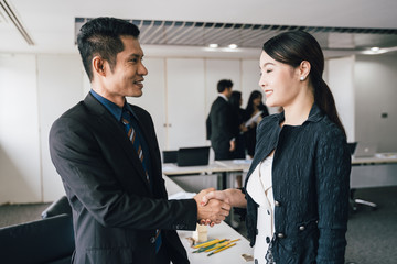 Businessman and Businesswoman shaking hands and discussion with colleague in meeting room or conference room and audience.