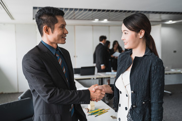 Businessman and Businesswoman shaking hands and discussion with colleague in meeting room or conference room and audience.