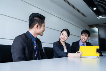 Confident businesswoman sitting at table and signing paperwork of his partner and smiling after...