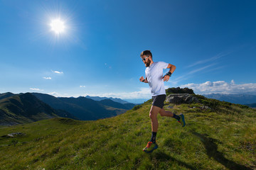 Fototapeta premium Athlete man practicing mountain running in the sun at high altitude
