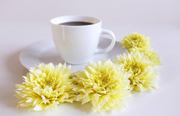 A cup of black coffee and yellow dahlia flower on the table.