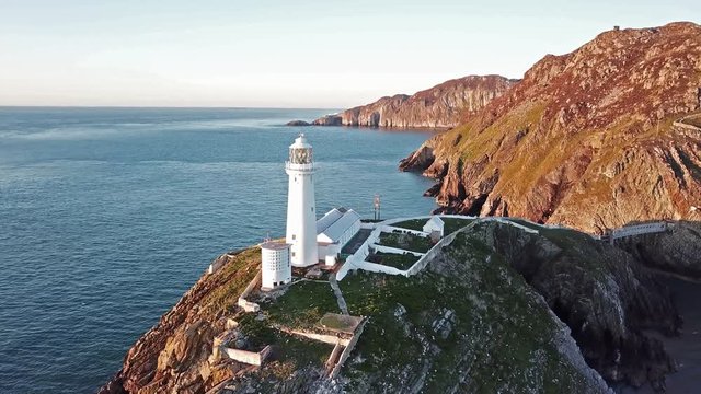 Aerial view of South Stack with lighthouse and cliffs during sunset