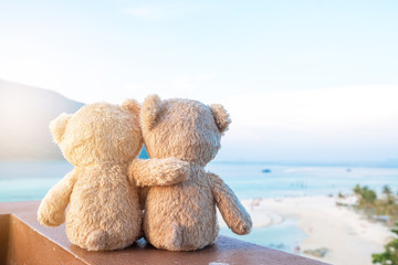 Two teddy bears sitting sea view. Love and relationship concept. Beautiful white sandy beach in the...