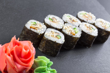 Japanese restaurant, sushi roll on black slate plate.