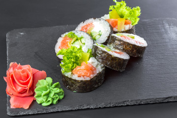 Japanese restaurant, sushi roll on black slate plate.