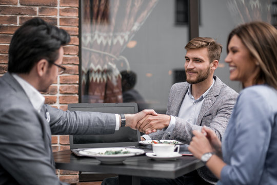 Business Partners Greet Each Other In The Cafe.