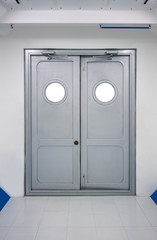 Grey swing doors with circlie windows and automatic hydraulic leaver hinge door.