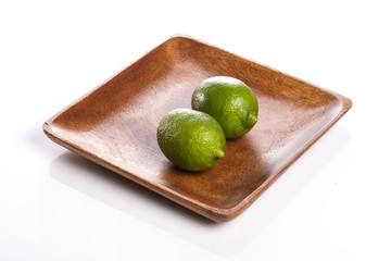 two fresh green limes on the wood tray isolated white