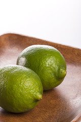two fresh green limes on the wood tray isolated white