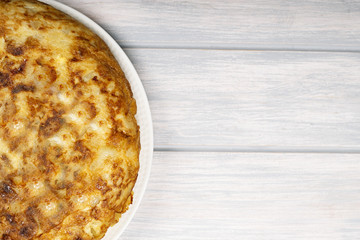 Spanish potato omelette on white wooden background. Typical spanish food.