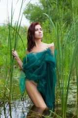 Fototapeta premium a young woman is standing on a swamp, covered by a green cloth