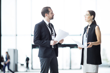 Two young elegant economists discussing points of their reports or ideas for conference