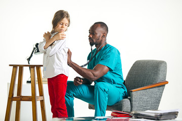 The healthcare and medical concept - african male doctor with stethoscope listening to child chest in hospital. The doctor, health, medicine, patient, pediatrician, illness concepts